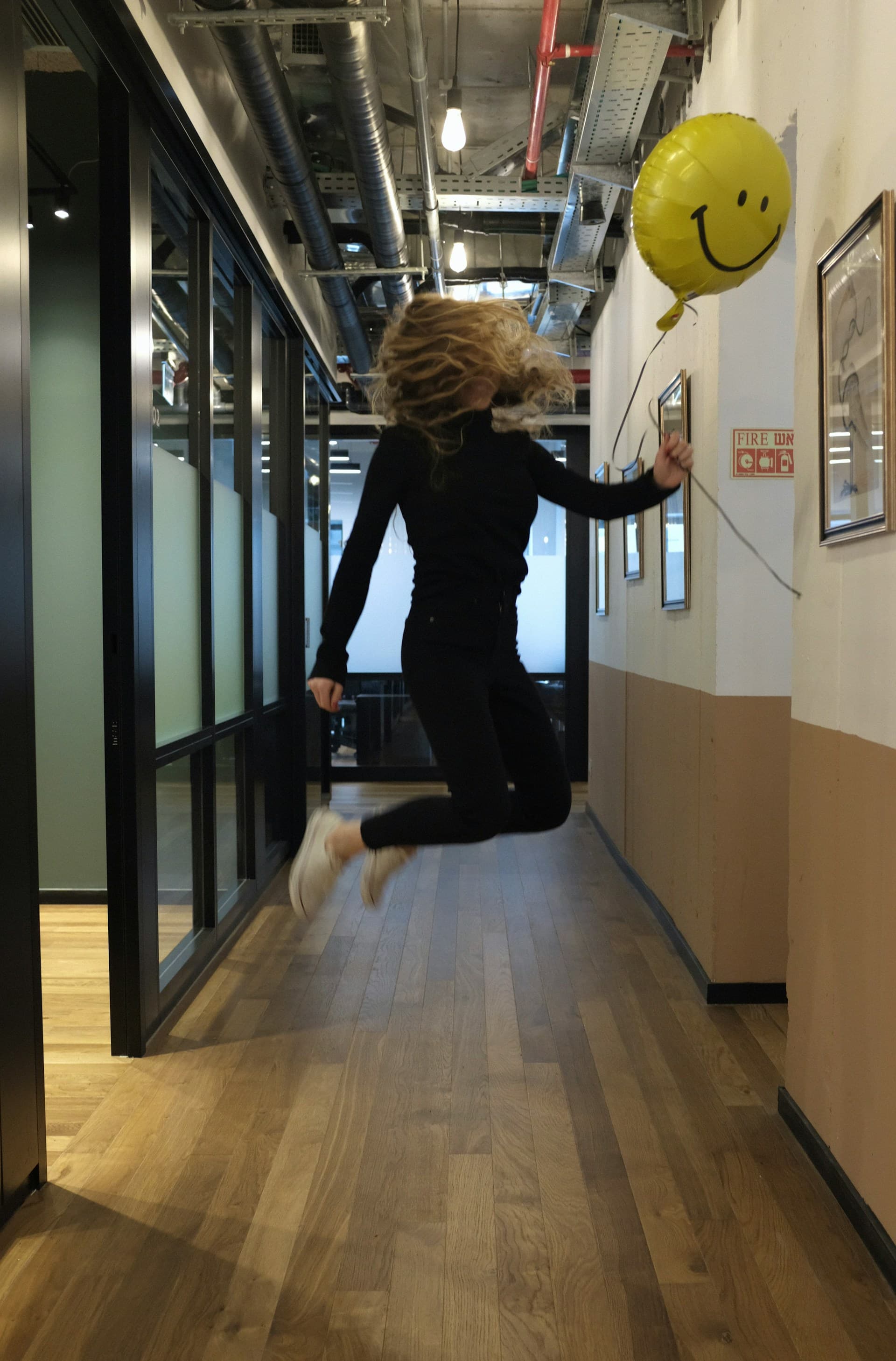 A person jumping with a smiley-face balloon